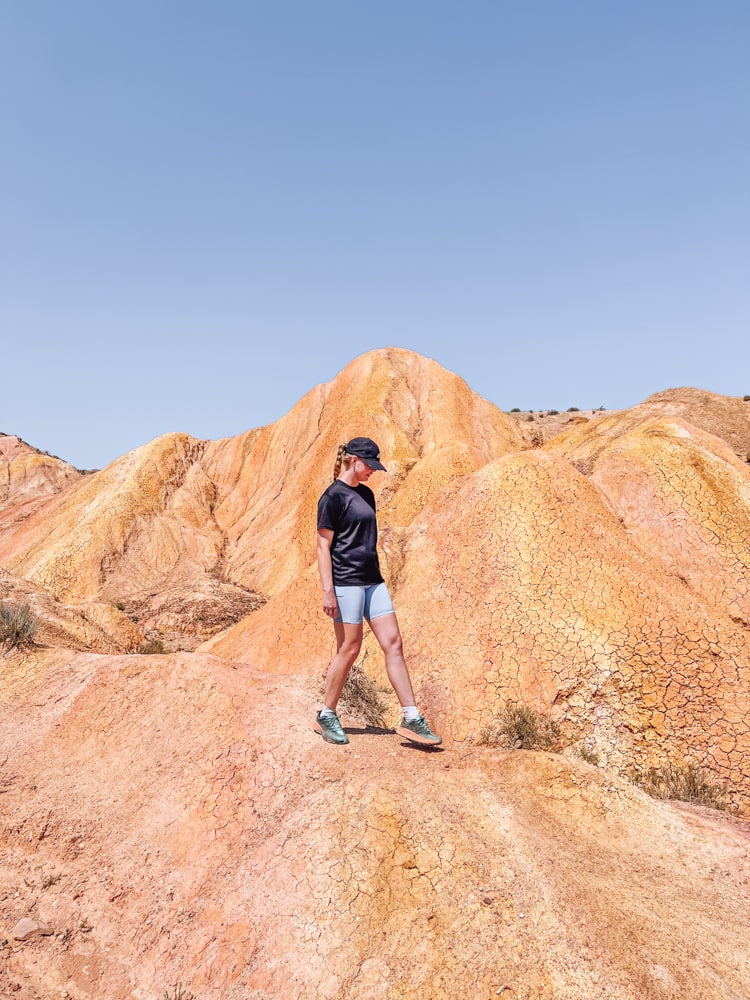 A girl standing on colorful rock formations in Fairy Tale Canyon in Kyrgyzstan